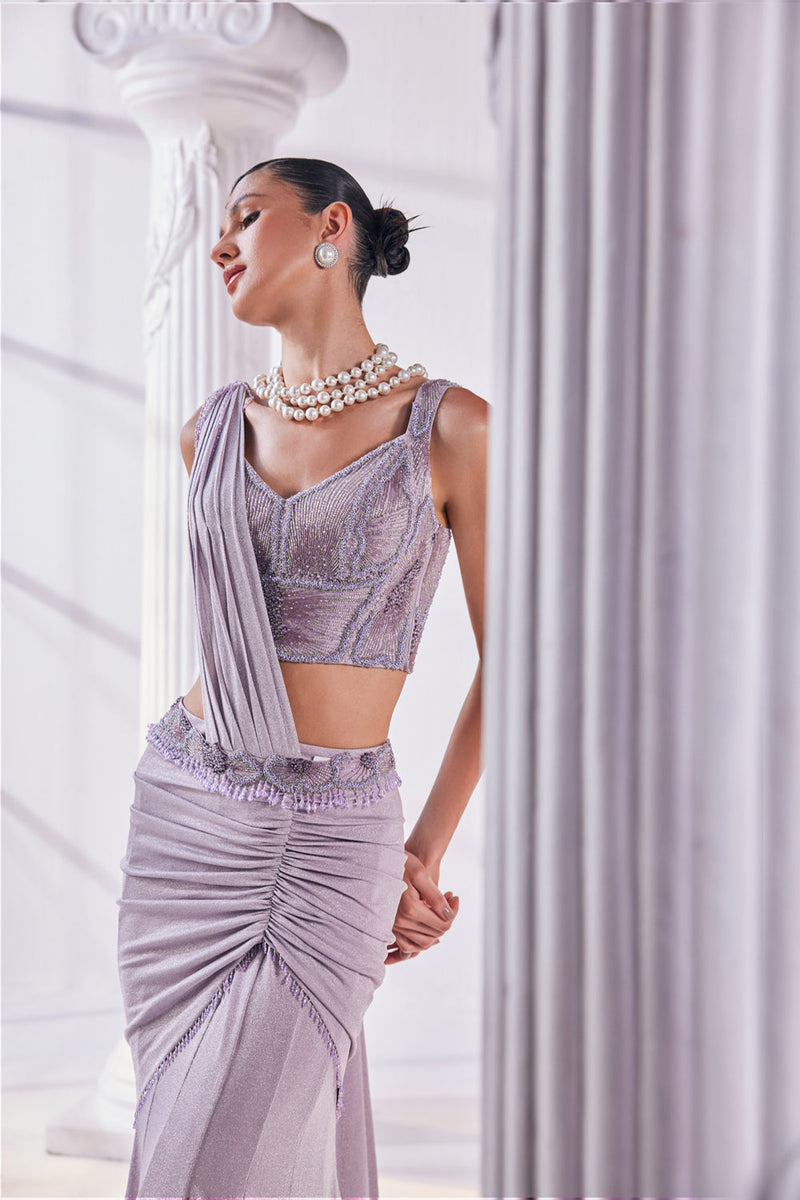 Draped Saree In Luxurious Shimmer Lycra Designed In Lilac Colour, An Emroidered Corset And A Belt.