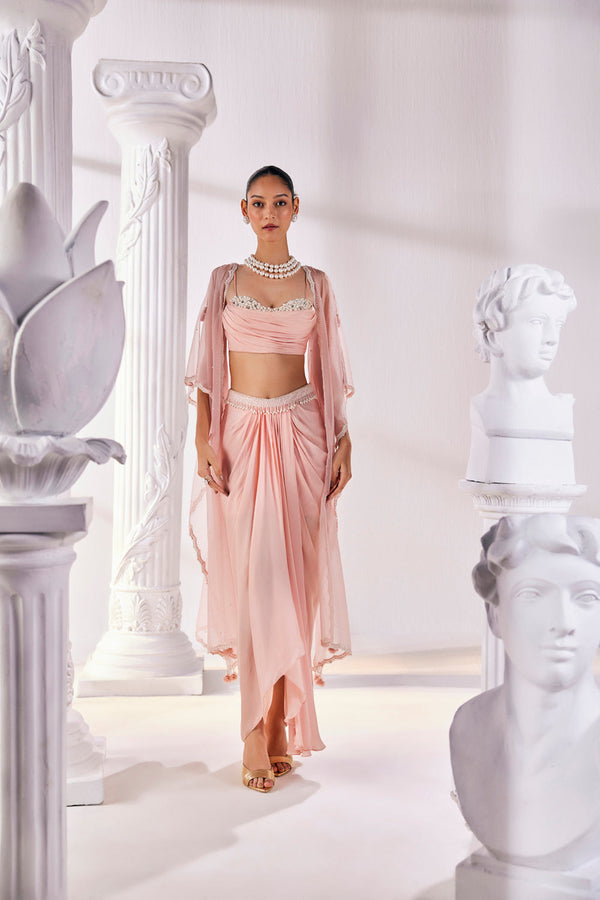 Peach Draped Skirt In Satin Georgette Paired With A Belt And A Pearl Detailed Blouse With A Soft Organza Cape.